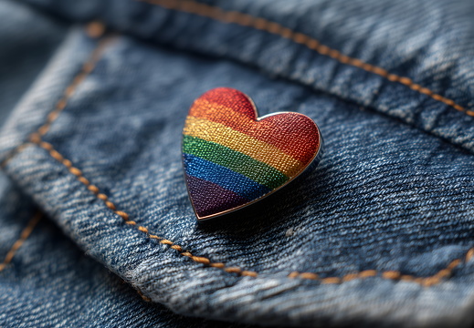 Gewebter Regenbogen-Herz-Pin auf Jeansstoff in Nahaufnahme