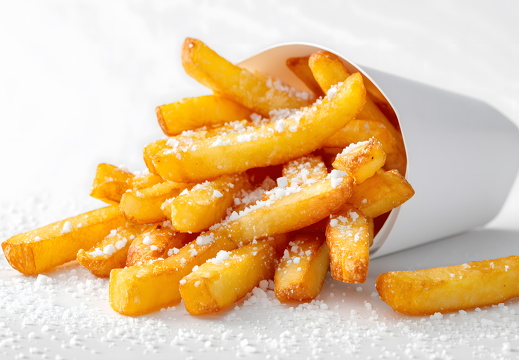 Knusprige Pommes mit Salz auf weißem Papier isoliert