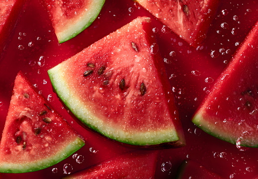 Frische Wassermelonen mit Tropfen auf rotem Hintergrund