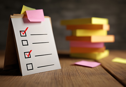 Checkliste mit Häkchen und Klebezetteln auf Schreibtisch