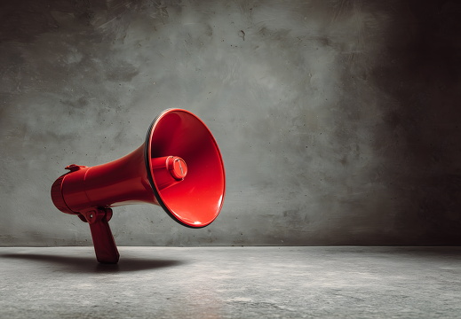 Rotes Megafon auf Betonboden mit Lichtspiel