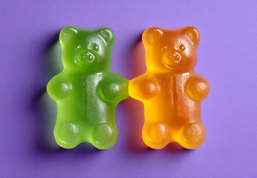 Zwei Gummibären in Grün und Orange auf lila Hintergrund