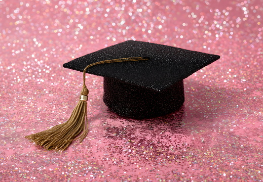 Abschlusskappe mit goldener Quaste auf glitzerndem Hintergrund