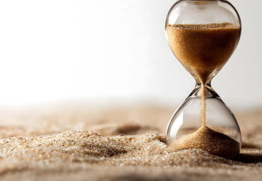 Klassische Sanduhr im Sand als Symbol für Zeitverlauf